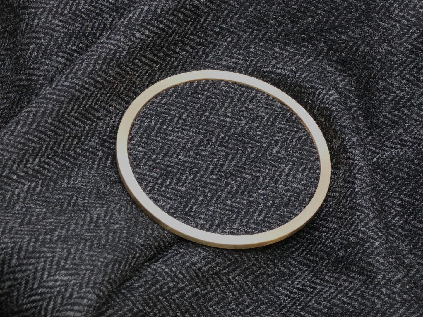 Black Herringbone Tweed Brass Coaster on Fabric