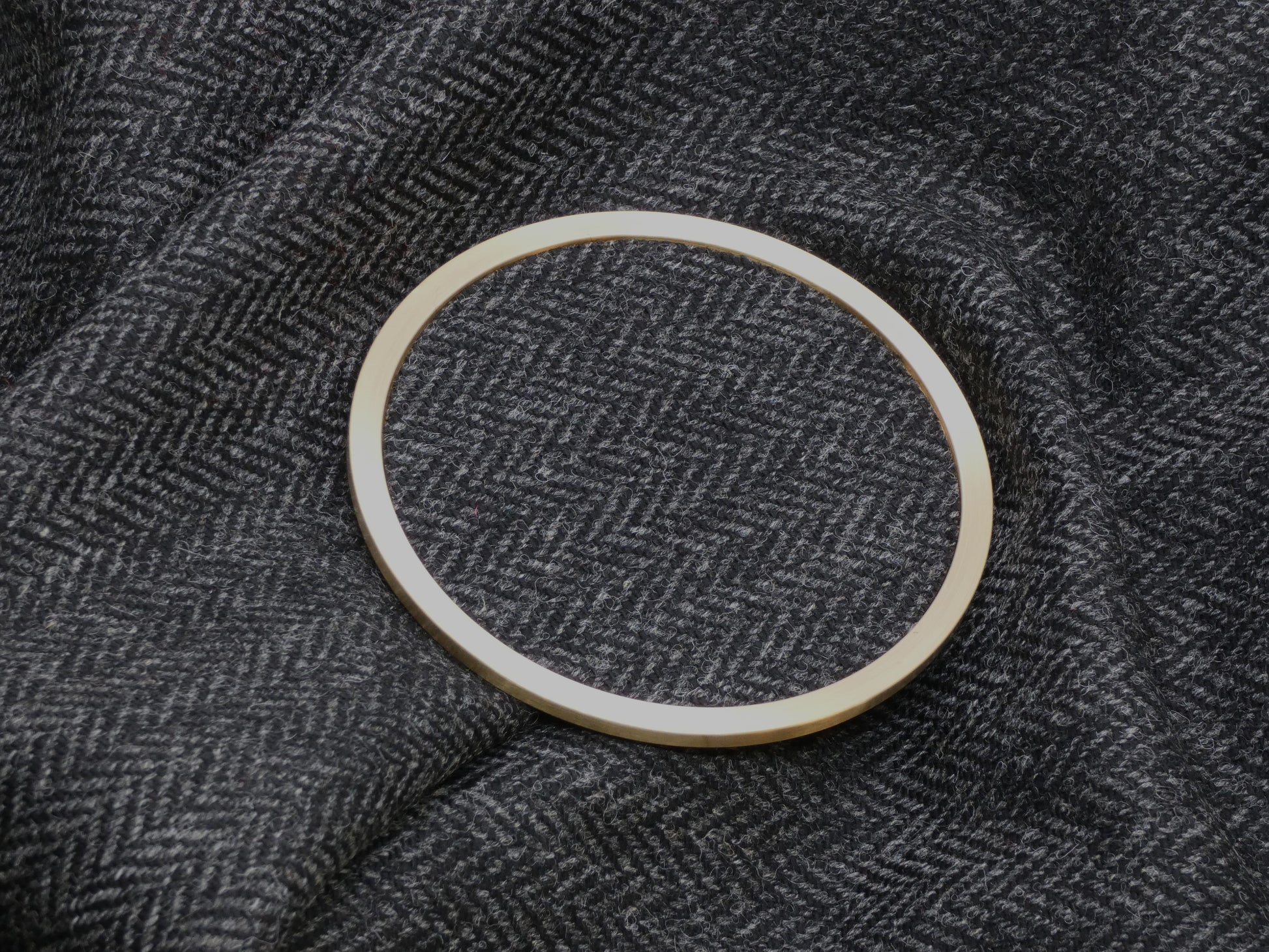 Black Herringbone Tweed Brass Coaster on Fabric