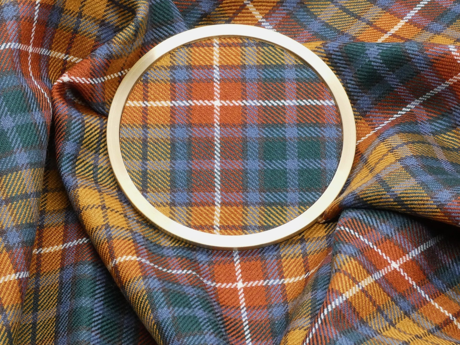 Buchanan Tartan and Brass Coaster resting on tartan Fabric Wool