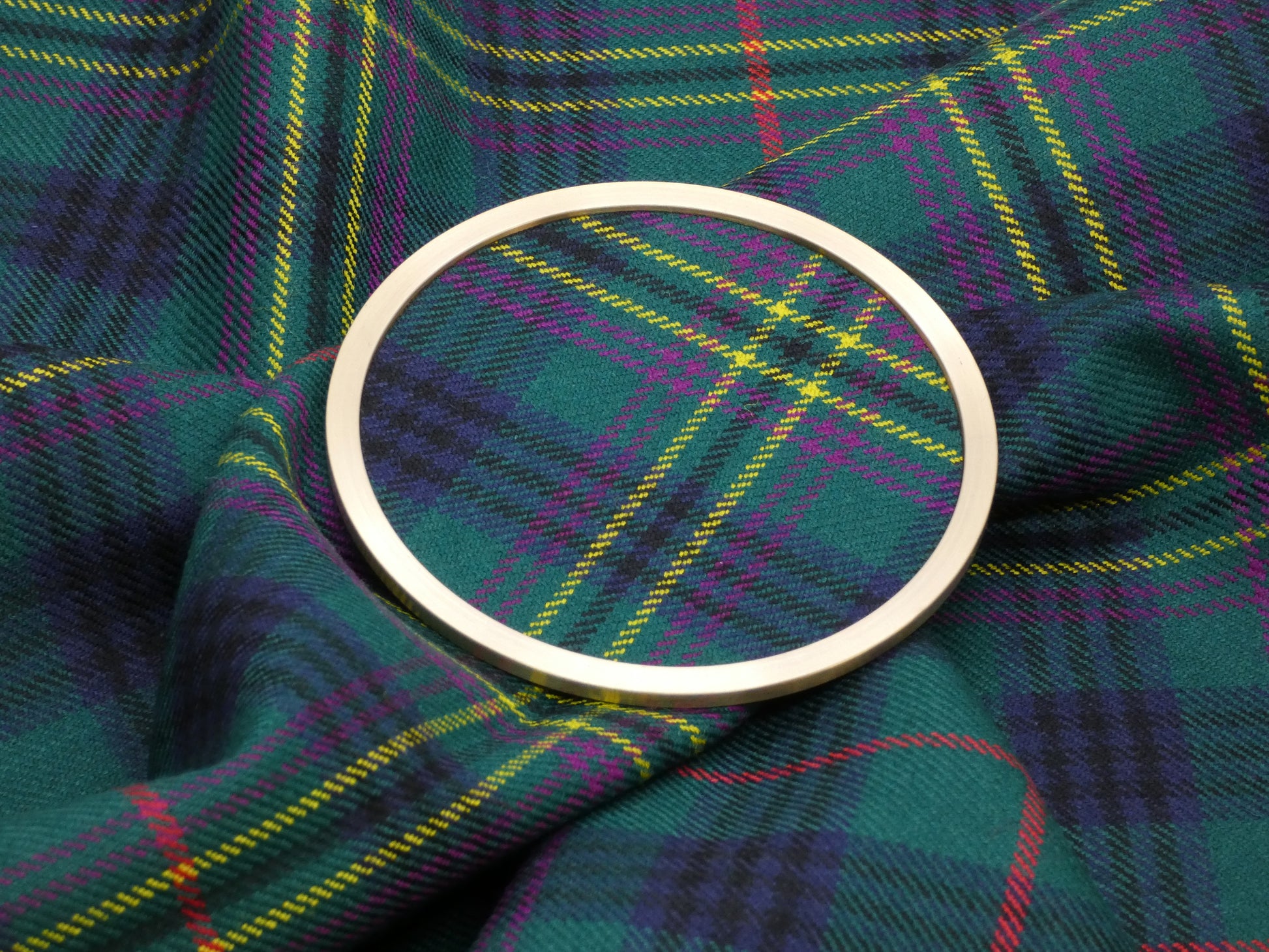Clan Kennedy Ancient Tartan Brass Coaster on Tartan Fabric