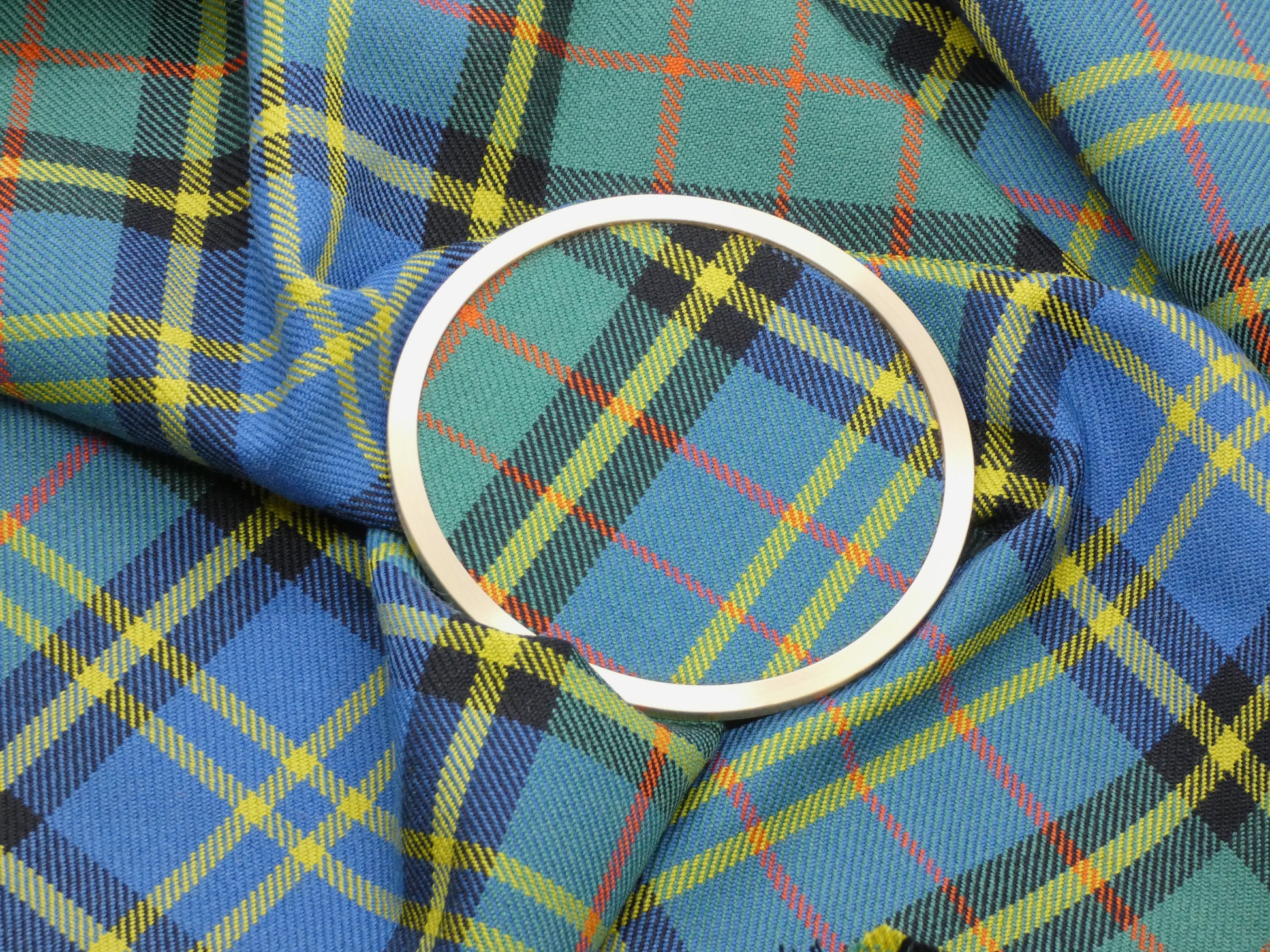 MacMillan Hunting Ancient Tartan Brass Coaster on Tartan Wool Fabric